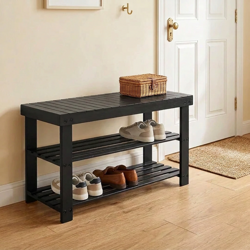 Black bamboo shoe bench in an entryway with shoes and a basket on the shelves