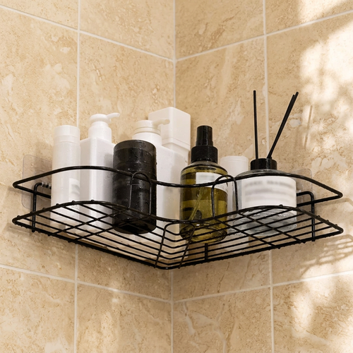 Black wire corner shower shelf with bottles mounted in a beige tile corner without drilling