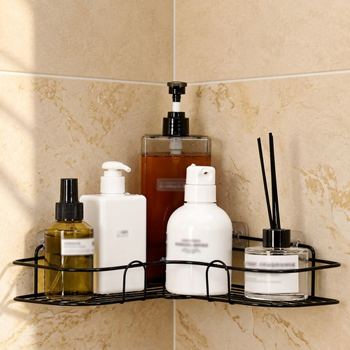Black corner shower caddy holding shampoo, soap and a diffuser in a beige tile shower corner